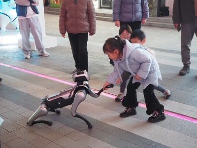 在文三数字生活街区的广场，小朋友正在和机器狗握手（图片：王如影）.JPG